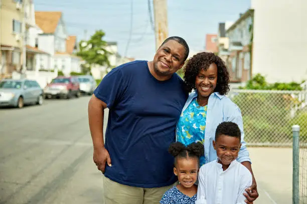 Parents and two kids smiling on a neighborhood street in navy, white, and blue floral outfits